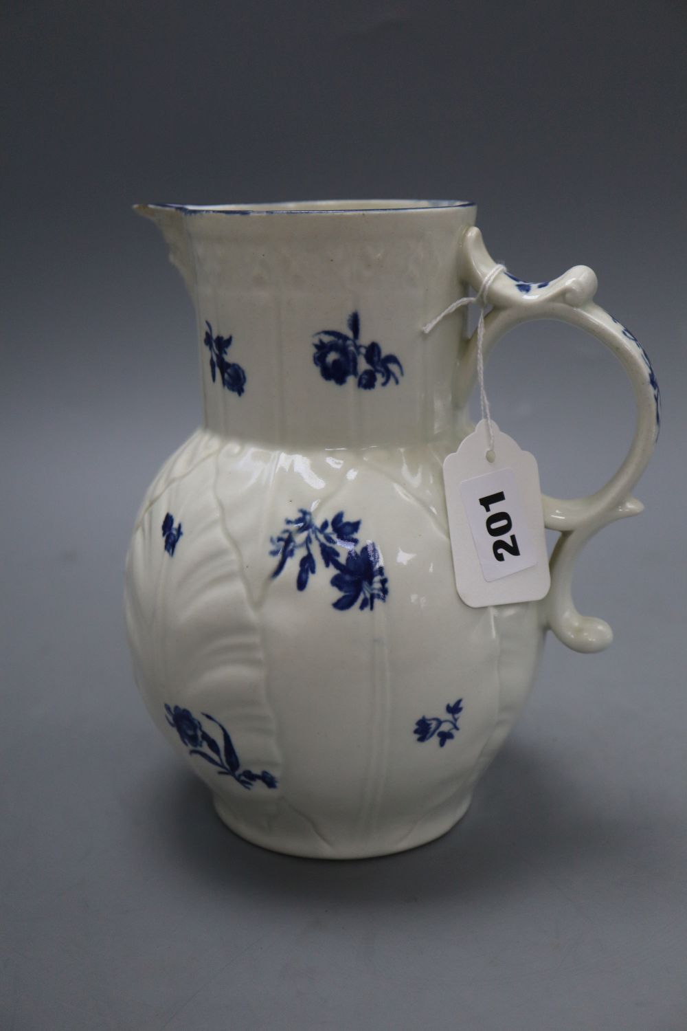 A Caughley cabbage leaf mask jug, c.1780, with scroll handle, decorated with floral sprays in underglaze blue, crescent mark, height